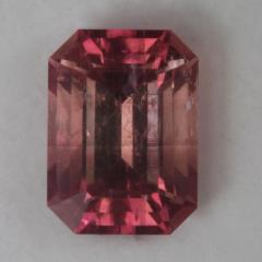 Slightly included, dichroic peach emerald cut.