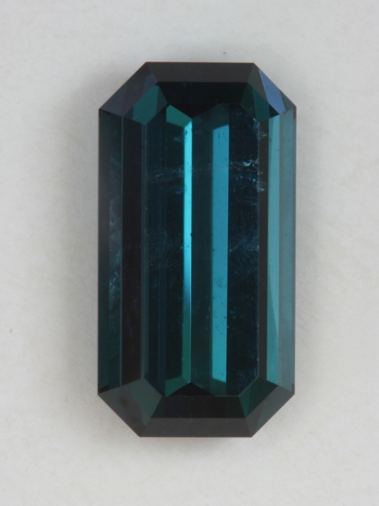 Dark toned, blue shifting toward green, closed ended emerald cut.